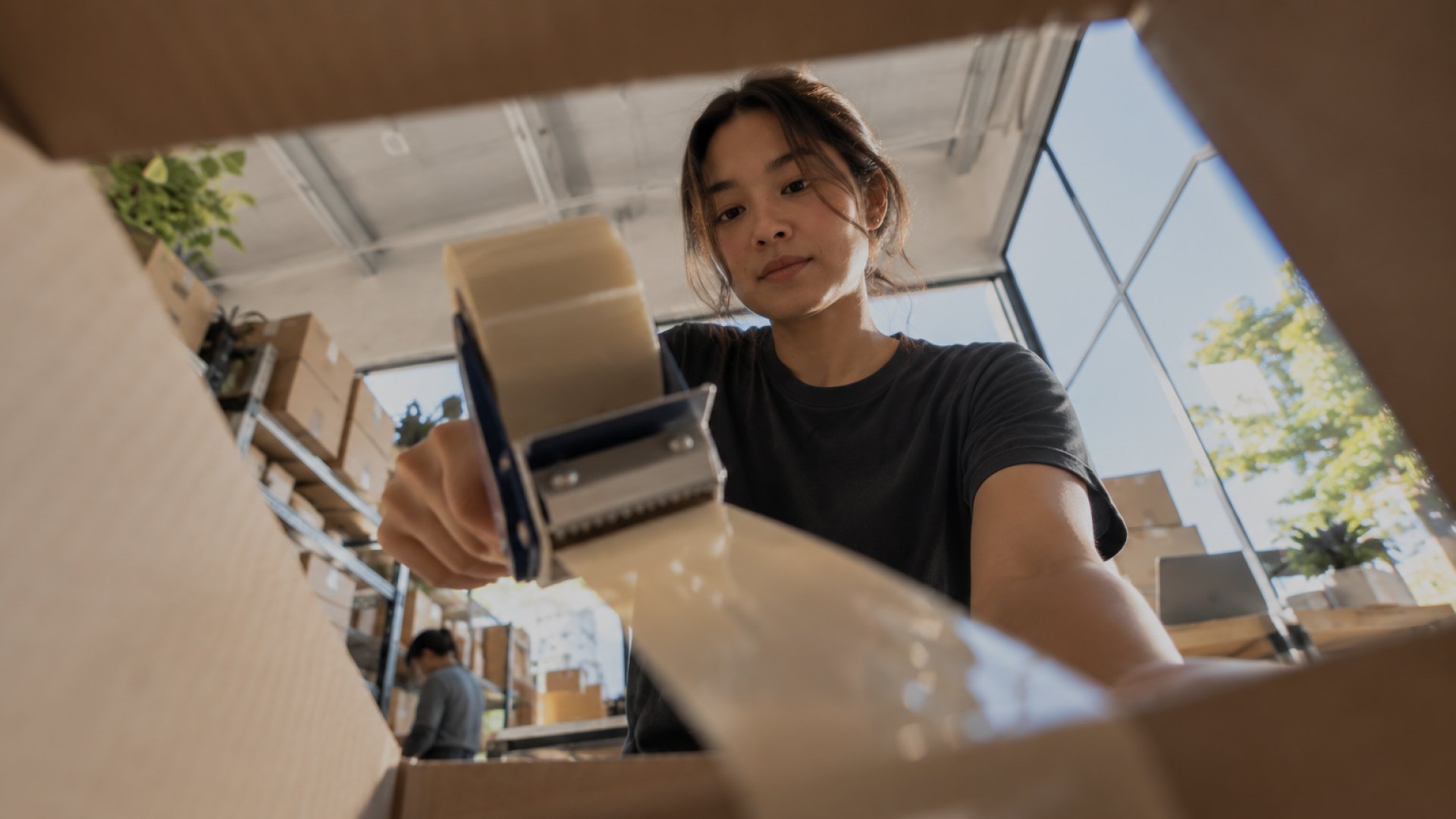 A woman packing a parcel into a cardboard box